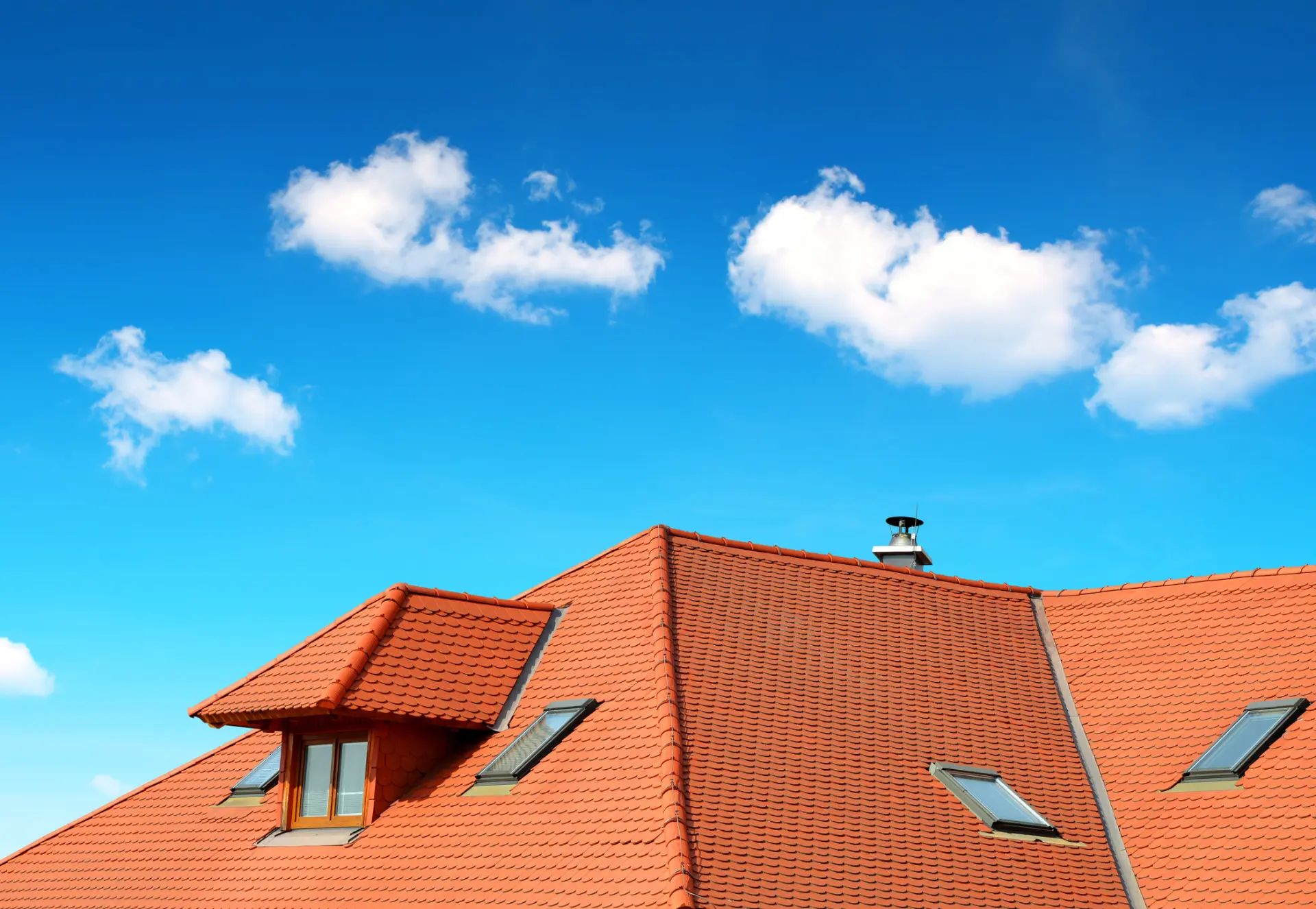 Toit avec tuiles en terre cuilte avec un ciel bleu et des nuages